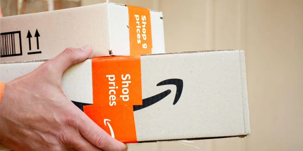 Hand holding Amazon packages outside of a door