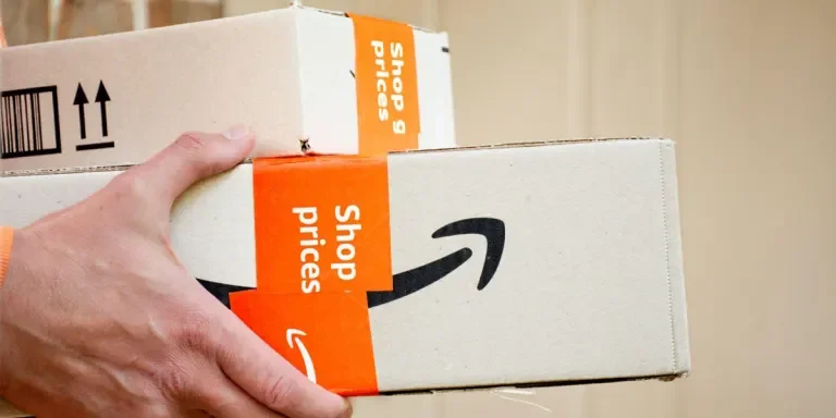 Hand holding Amazon packages outside of a door