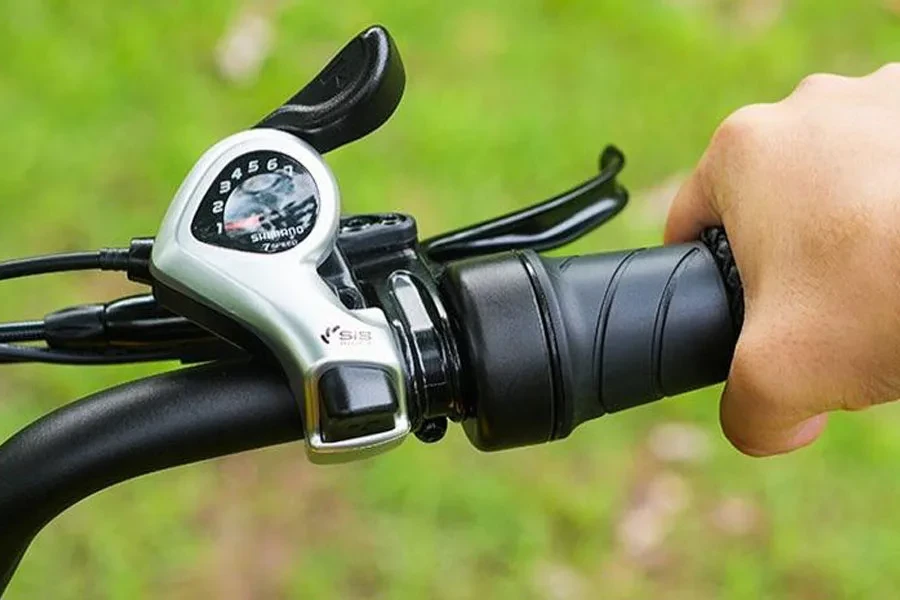 Mão segurando o acelerador de uma bicicleta elétrica