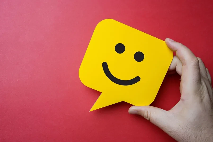 Hand holding yellow smiling speech bubble