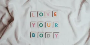 LOVE YOUR BODY written in titles on a white sheet