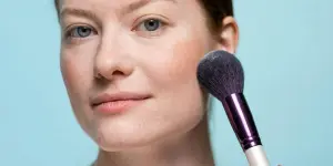 Señora aplicando rubor con una brocha de maquillaje