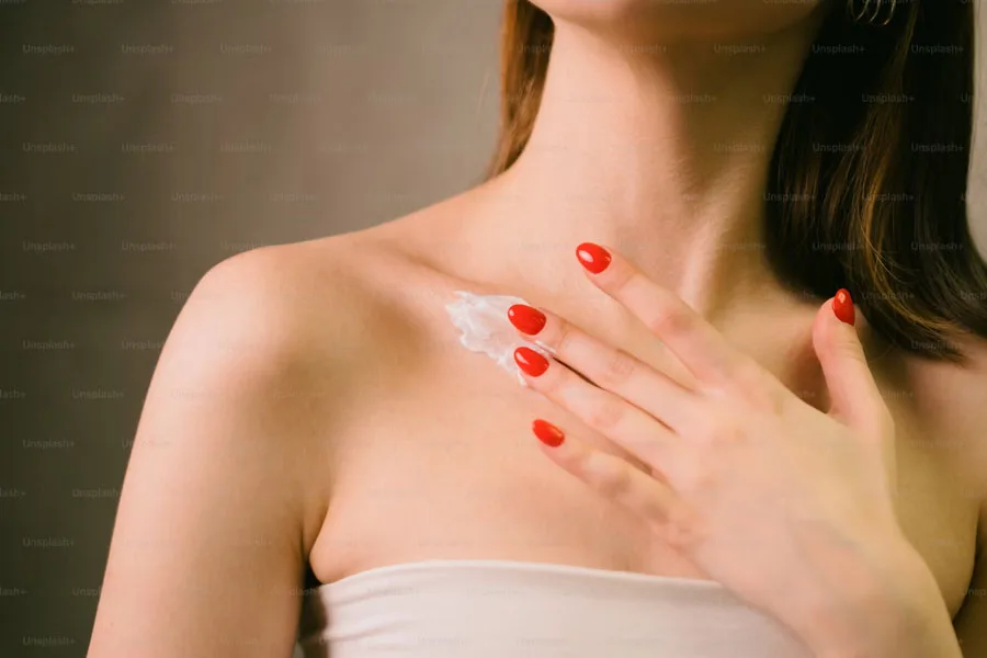 Lady applying moisturizer on her chest