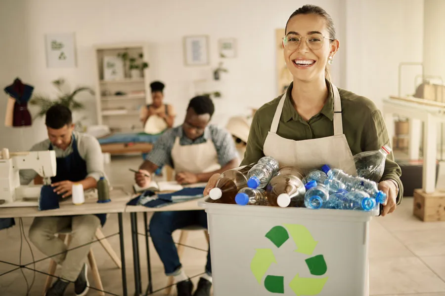 Lady holding a bucket of recyclable plastic bottles