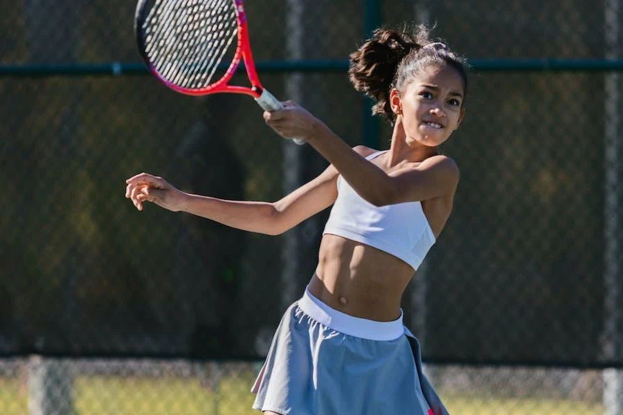 Wanita mengayunkan raket tenis merah