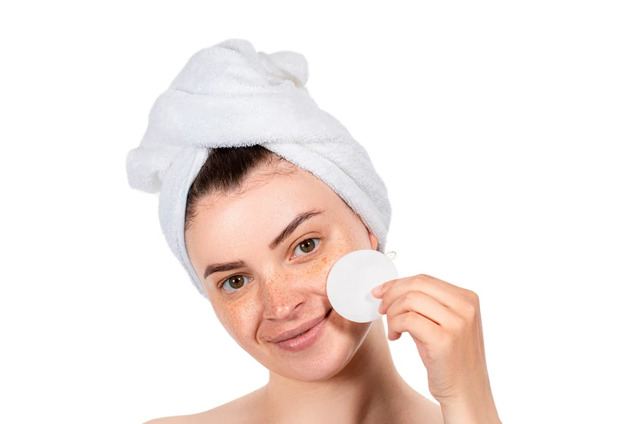 Dame souffrant d'acné utilisant un nettoyant pour le visage avec un tampon