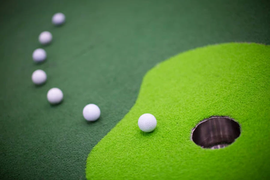Tikar golf besar dengan bola-bola berjejer di sekeliling lubang
