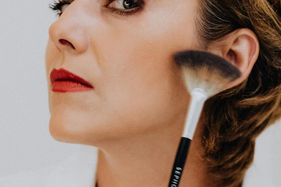 Hellhäutige Frau posiert mit einem Make-up-Pinsel