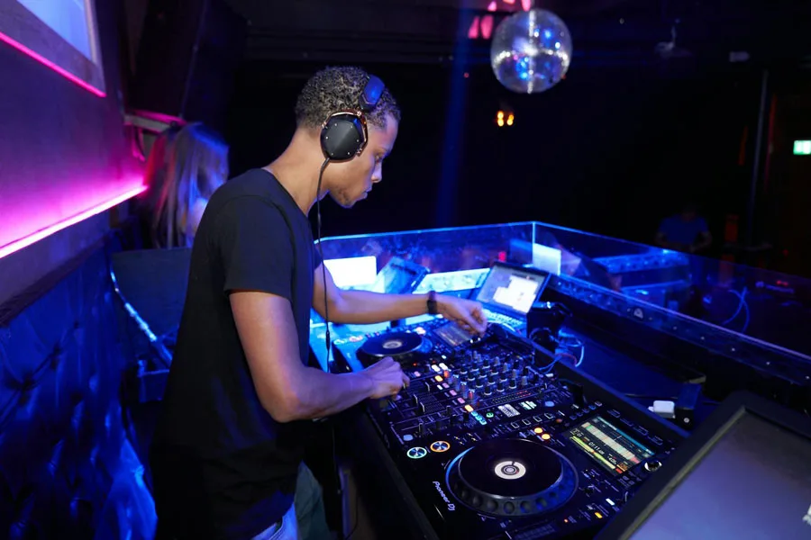 Мужчина в черной рубашке с круглым вырезом играет на проигрывателе DJ