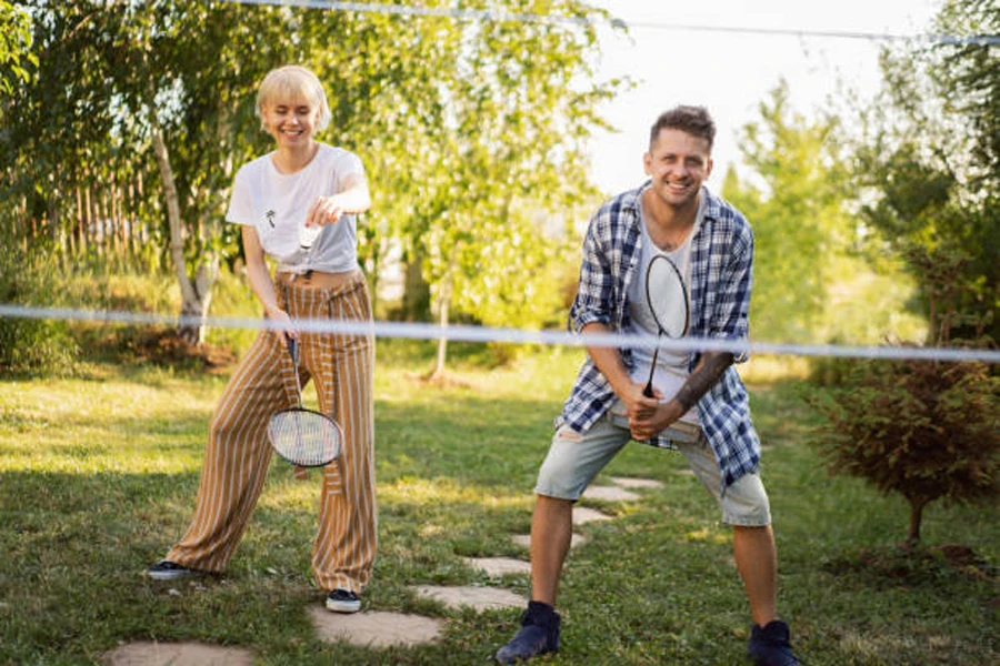 Hombre y mujer jugando dobles con juego de bádminton de jardín.