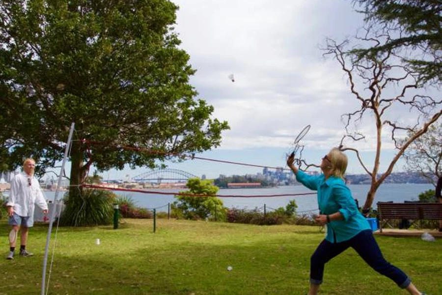 Nehrin yanında taşınabilir badminton seti kullanan kadın ve erkek
