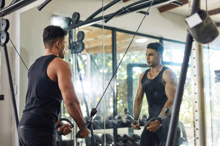 Pria melakukan latihan lengan di depan cermin gym