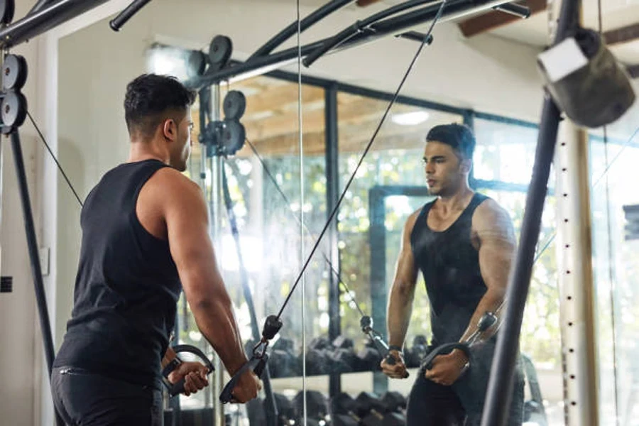 Man doing arm exercises in front of gym mirror