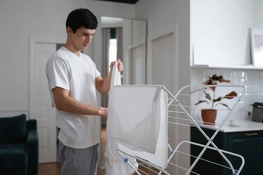 Man drying clothes on 3 tier folding laundry rack