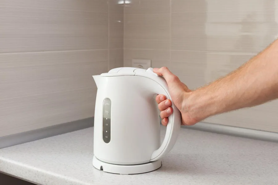 Man holding a white plastic electric kettle
