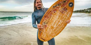 Man holding a wooden skimboard