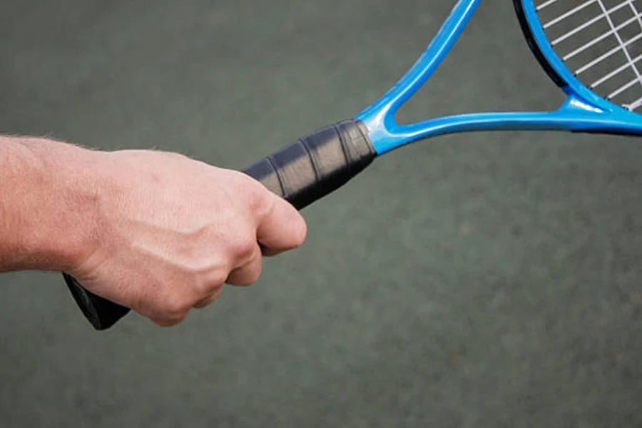 Man holding blue tennis racquet with black overgrip
