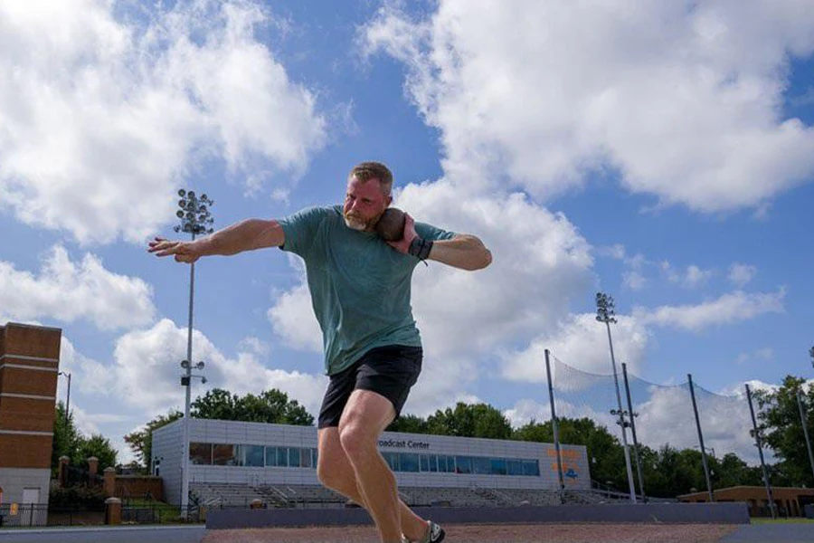 Man in half-tights engaging in a shot put training session