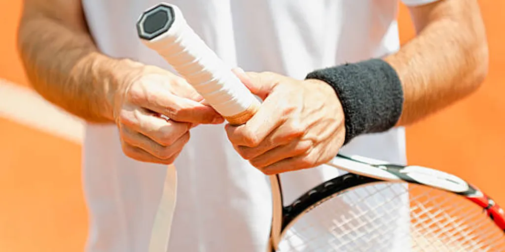 Hombre poniendo empuñadura de raqueta de tenis alrededor del mango de tenis