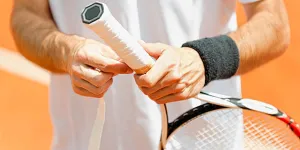 Homem colocando o punho da raquete de tênis no cabo do tênis