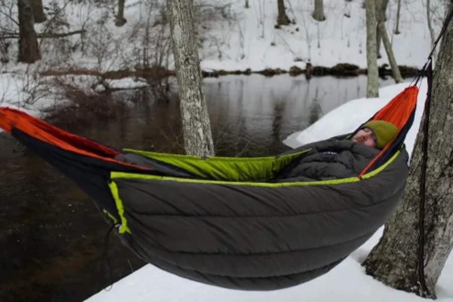 Mann schläft im Winter in Hängematte mit Schlafsack