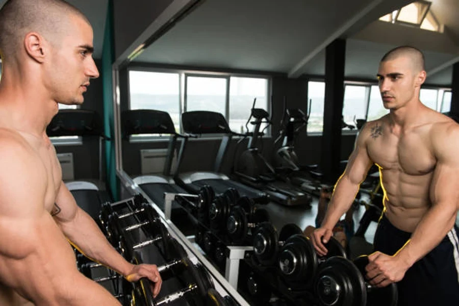 Man standing with dumbbell rack in front of mirror