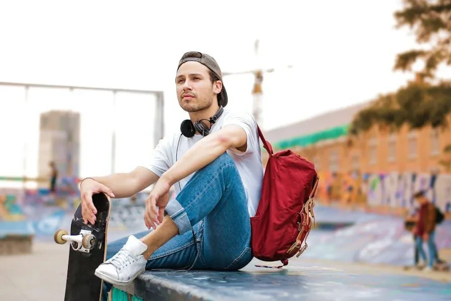 Man with a red backpack holding a skateboard