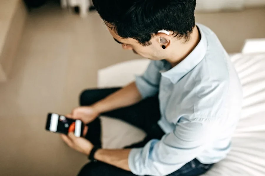 Man with hearing aid scrolling his phone