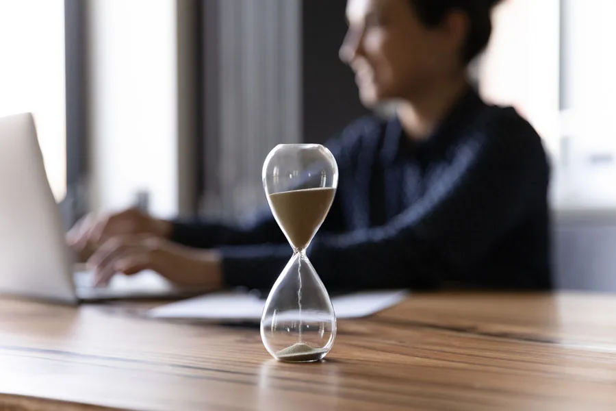 Man working next to an hourglass