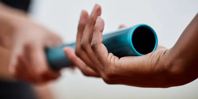 Metal teal relay baton being handed between runners