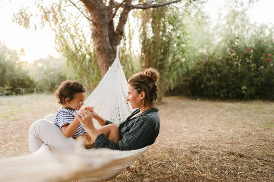 Mother and child sitting in white cotton portable folding hammock