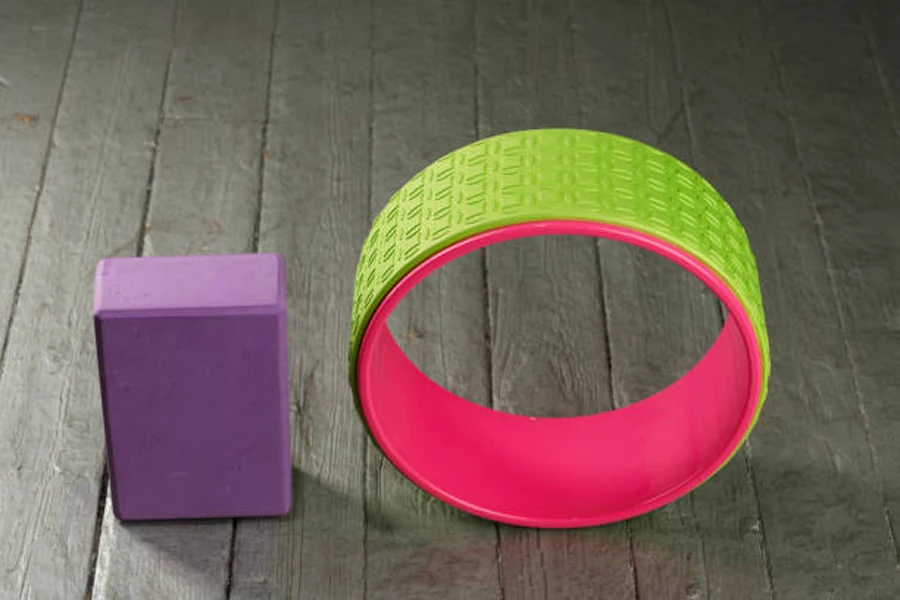 Neon-colored plastic yoga wheel next to yoga block