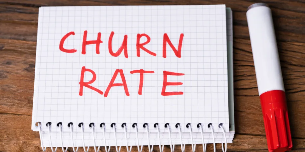 Bloc de notas con el texto "CHURN RATE" junto a un marcador rojo