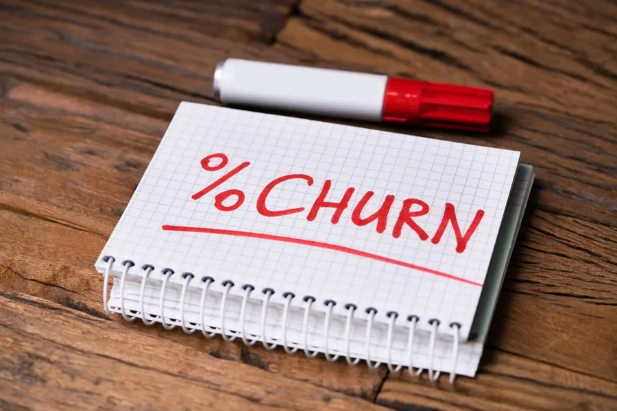 Notepad with “% CHURN” text near marker on desk