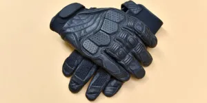Pair of black heated motorcycle gloves on beige background