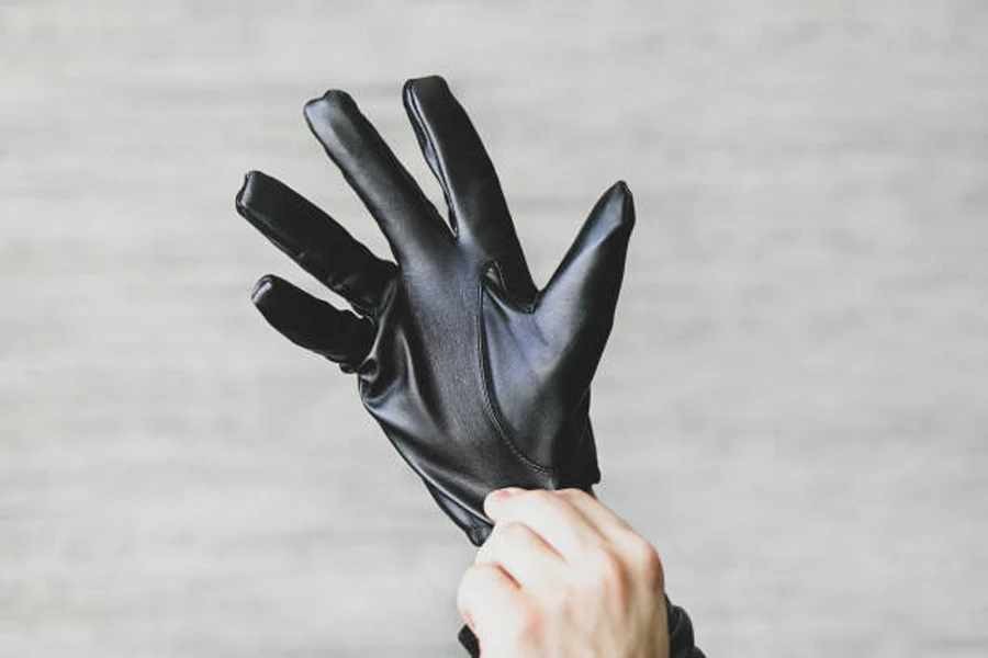 Pair of black leather motorcycle gloves being put on hand