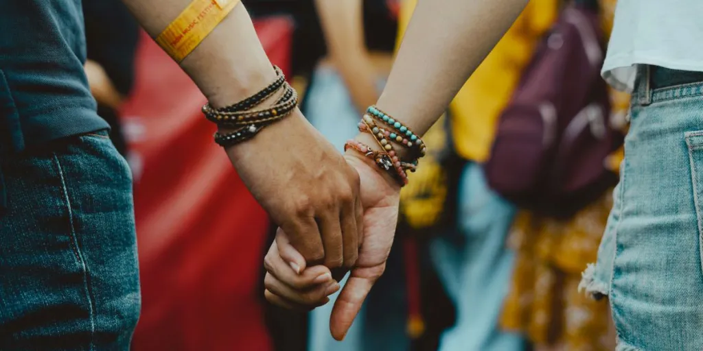 Orang-orang memakai gelang bertumpuk berpegangan tangan