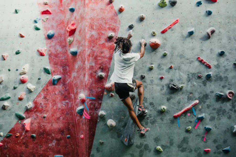 Person climbing an indoor wall using climbing chalk for grip