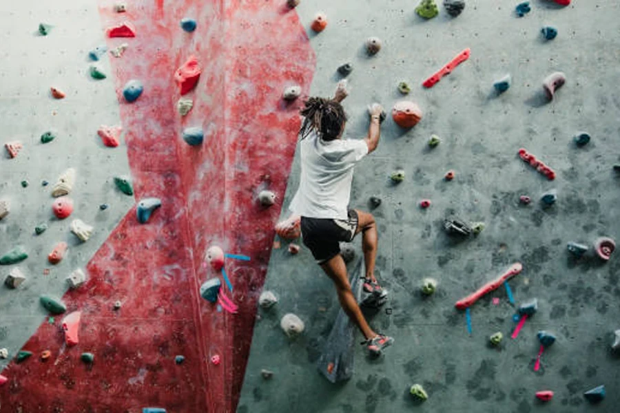 Pessoa escalando uma parede interna usando giz de escalada para se segurar