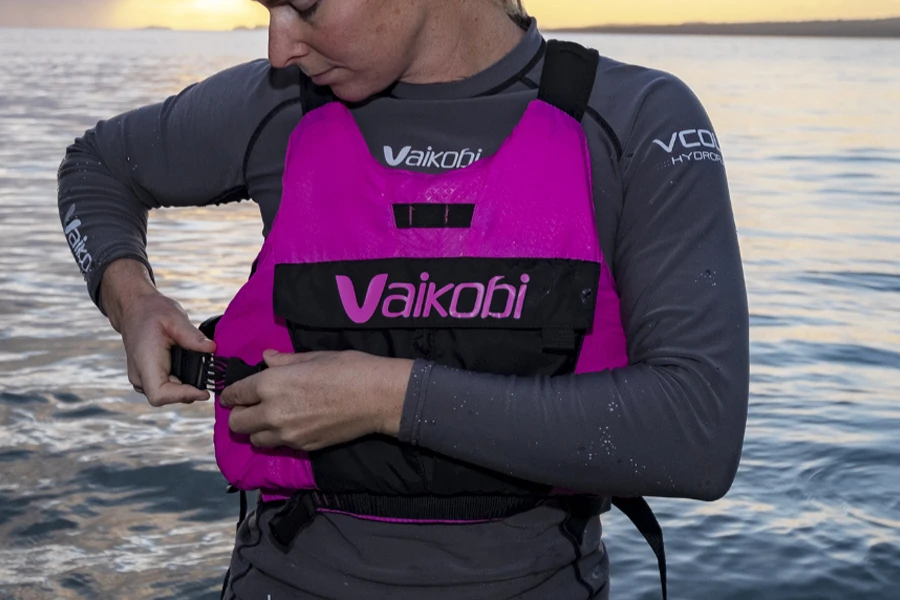 Person equipping a bright pink hybrid life jacket