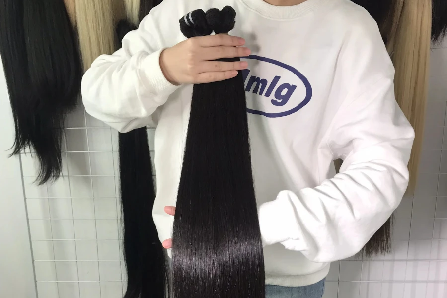 Person holding bundles of sew-in hair extensions