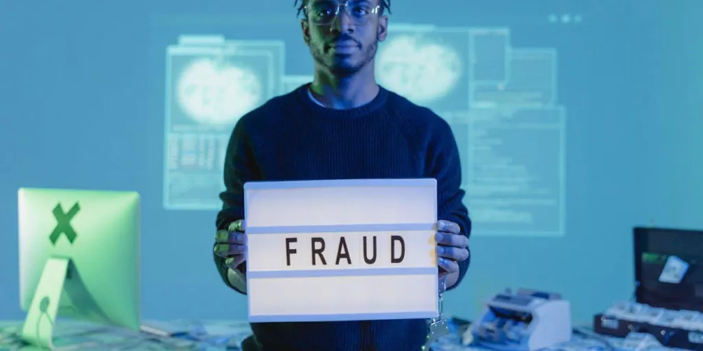Person holding up a sign that says ‘FRAUD’