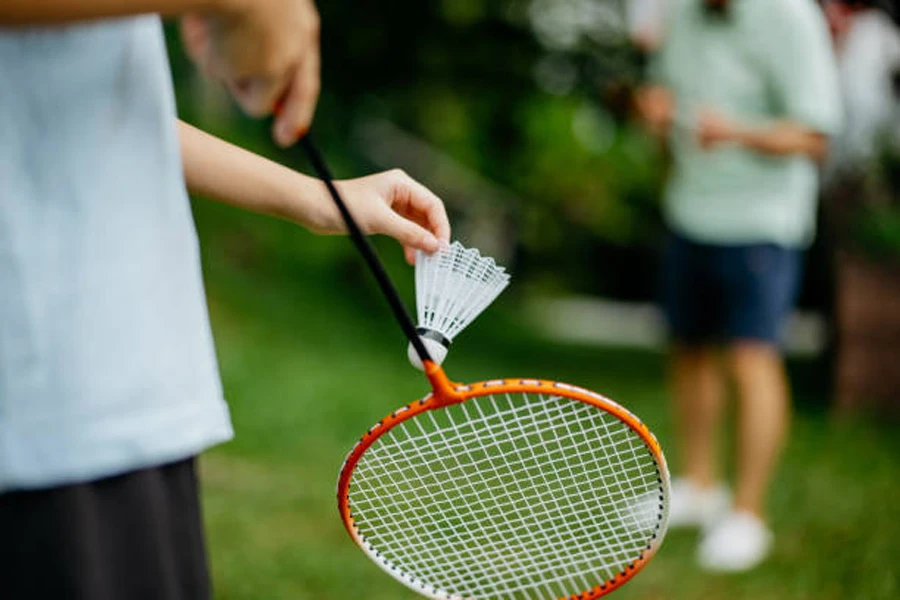 Person lining up shuttlecock on racket to serve outdoors