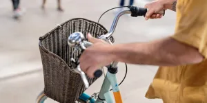 Pessoa empurrando bicicleta vintage com cesta de vime para bicicleta