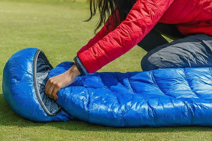 Person setting up a blue sleeping bag