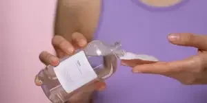 Person soaking a cotton pad with a toner