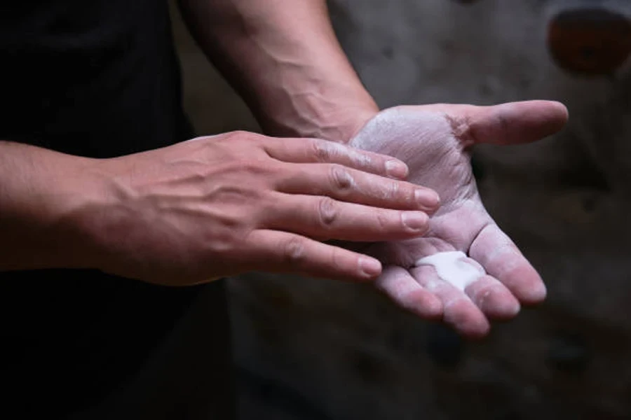 Personne répandant de la craie liquide sur la paume de la main