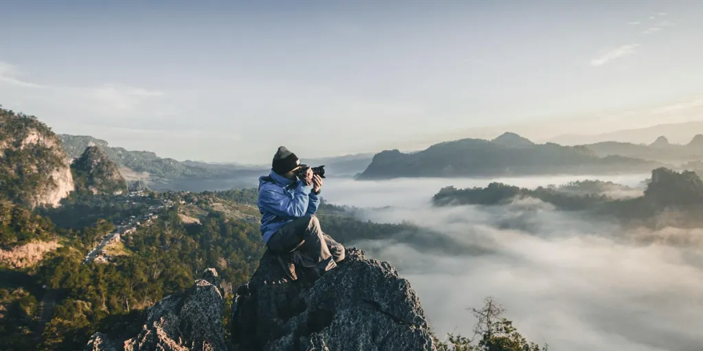 Persona tomando una fotografía en la cima de una montaña.
