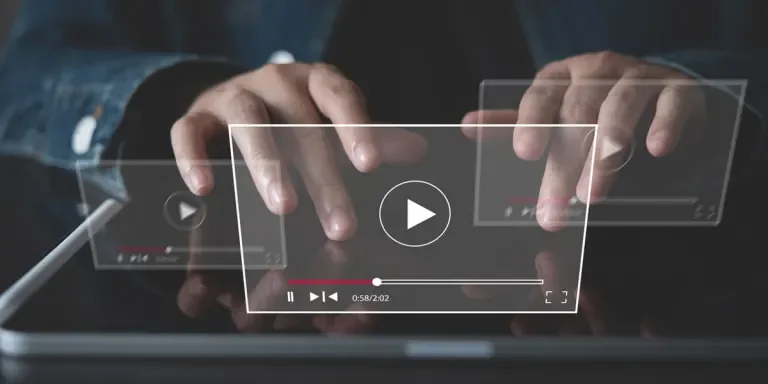 Person typing on a screen with video symbols hovering