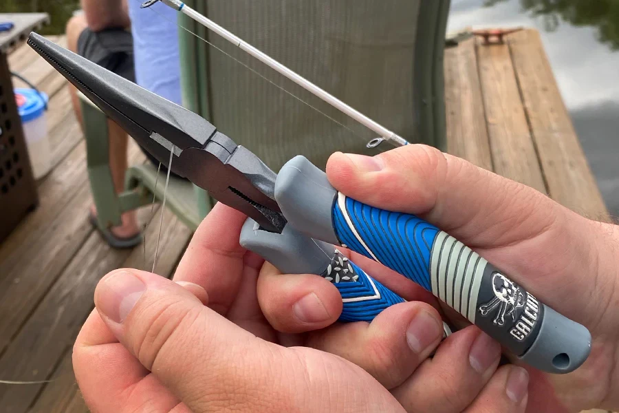 釣り用ペンチを使って糸を切る人